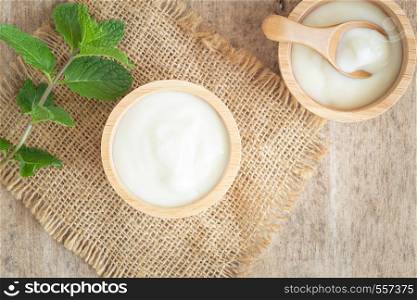 top view of natural greek yogurt in cup on old wooden table background. Yogurt is delicious tasty and healthy.
