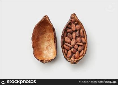 Top view of natural pod of Theobroma cacao tree in halves filled with unpeeled aromatic beans on white background. Halved pod of cocoa tree with seeds