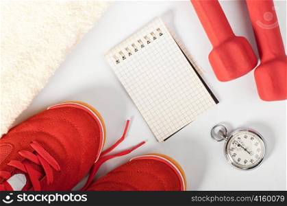 top view of notes, towel, red sneakers, barbells and stopwatch