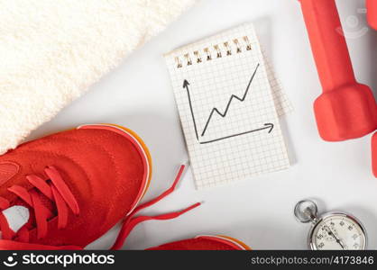 top view of notes, towel, red sneakers, barbells and stopwatch