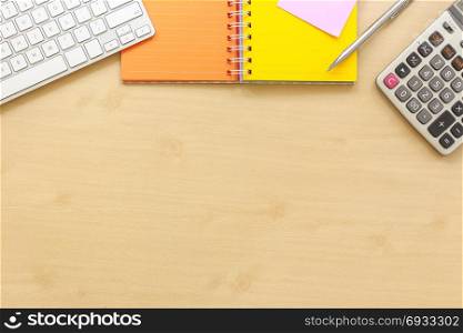Top view of office desk with most blank space. Stationery, keyboard, colorful paper book, calculator and premium pen setting on top side. Work planning and outsourcing, mockup background template.