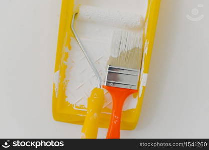 Top view of paintroller and paintbrush in tray over white background. Refurbishment, repairing and decoration concept. Horizontal shot