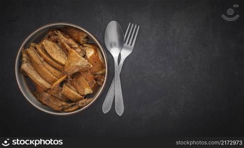 top view of Ped Pa Lo, tasty brown Chinese stewed duck in bowl with spoon and fork on dark gray, grey, black tone texture background with copy space for text