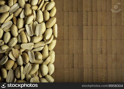 top view of peeled peanuts seeds close up on  bamboo wooden background for copy space.  arachis hypogaea  Edible seeds. Healthy snack nutrition concept