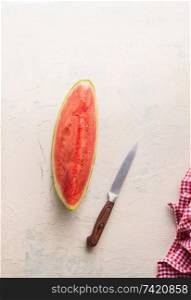 Top view of piece of watermelon on white table with knife. Juicy refreshing summer food
