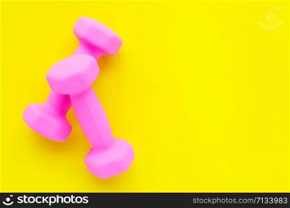 Top view of pink dumbbells isolated on yellow background. Copy space