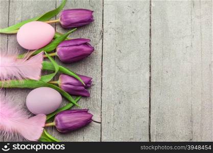 Top view of pink easter eggs and violet tulips over wooden table
