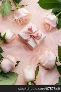 Top view of pink roses and gift box on pink tulle background. Surprise Valentine’s Day