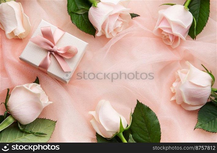 Top view of pink roses and gift box on pink tulle background. Surprise Valentine’s Day