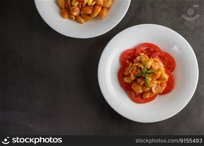 Top view of pipe rigate italian pasta with tomato sauce on tomato slice in white dish, copy space