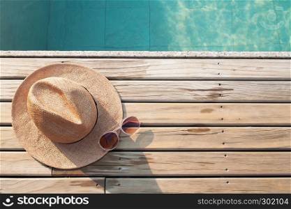 Top view of poolside, sun hat and sunglasses on wooden floor