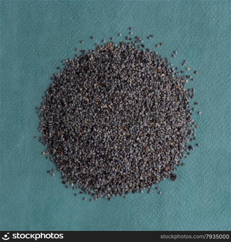 Top view of poppy seeds against blue vinyl background.