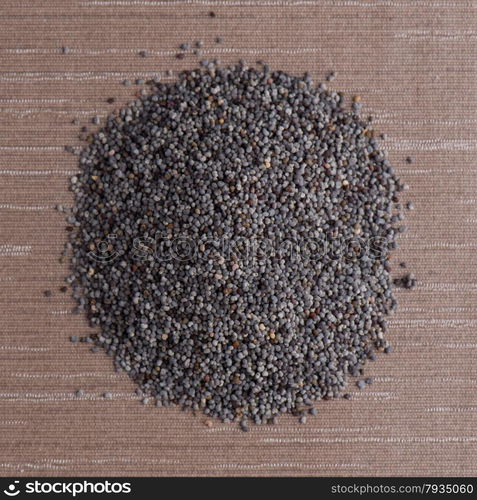 Top view of poppy seeds against brown vinyl background.