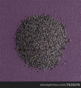 Top view of poppy seeds against purple vinyl background.
