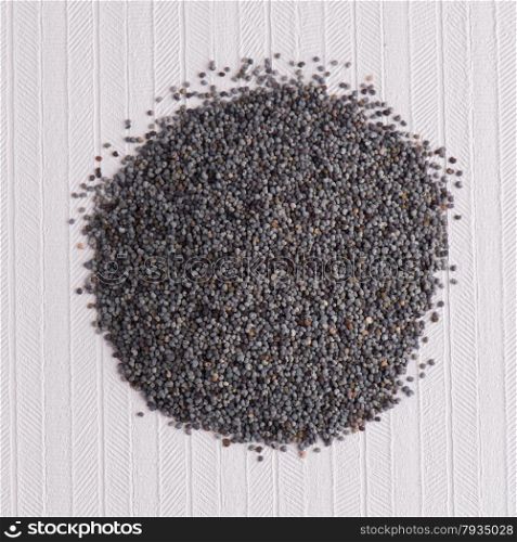 Top view of poppy seeds against white vinyl background.