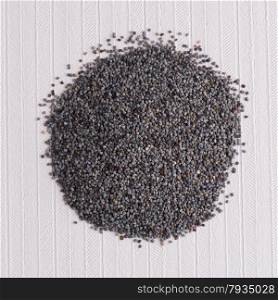 Top view of poppy seeds against white vinyl background.