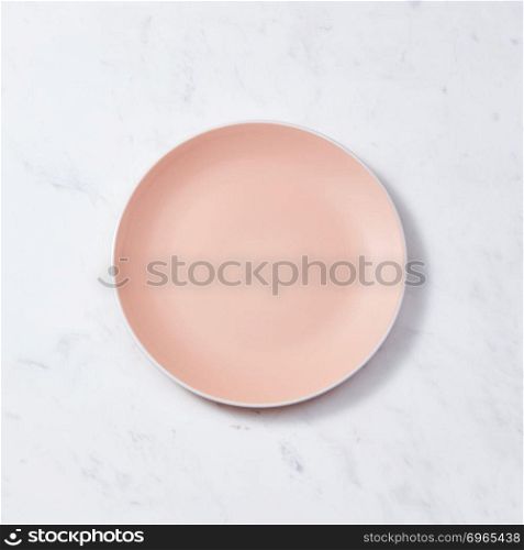 Top view of porcelain plate handmade. Ceramic glazed plate is empty on a gray background with copy space. Can be used for display or montage your products.. Traditional decorative handcrafted clay dish, covered with glazed on a gray concrete background. Flat lay