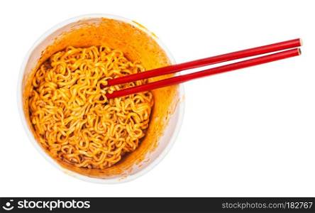 top view of red chopsticks in cup with prepared spicy instant noodles isolated on white background