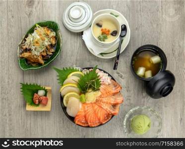 Top view of Samon don set with rice, egg stream, soup and ice scream over the wooden table, luxury japanese food concept