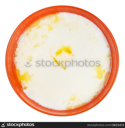 top view of semolina porridge with melting butter in orange bowl isolated on white background