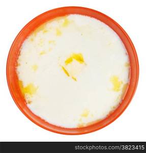 top view of semolina porridge with melting butter in orange bowl isolated on white background