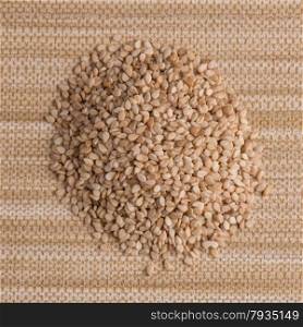 Top view of sesame seeds against beige vinyl background.