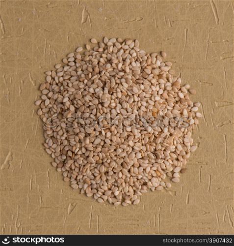 Top view of sesame seeds against brown vinyl background.