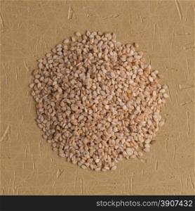 Top view of sesame seeds against brown vinyl background.