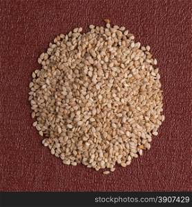 Top view of sesame seeds against red vinyl background.