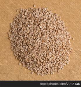Top view of sesame seeds against yellow vinyl background.