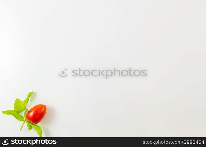 Top view of single cherry tomato and mint leaves isolated on a white background. Minimalist picture style with copy space for text