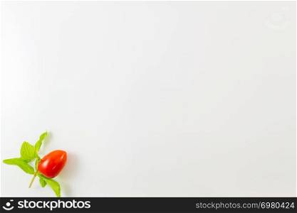 Top view of single cherry tomato and mint leaves isolated on a white background. Minimalist picture style with copy space for text