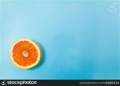 Top view of single grapefruit slice on blue background. Minimalist picture style with copy space for text