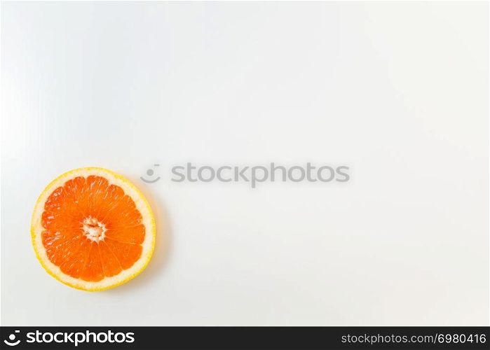 Top view of single grapefruit slice on white background. Minimalist picture style with copy space for text