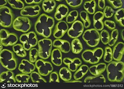 Top view of sliced raw green peppers on dark background. Top view of sliced green peppers on dark background