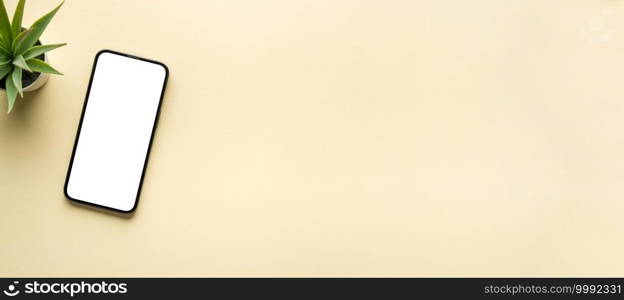 Top view of smartphone with blank screen and green plant on yellow background