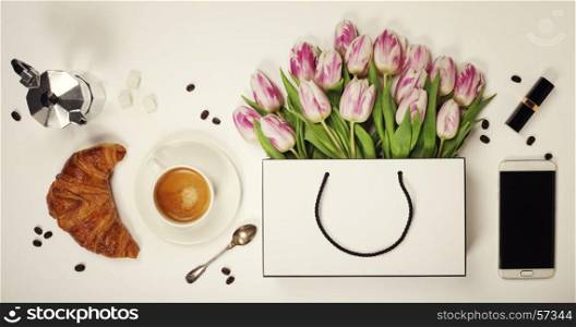 Top view of spring flowers, coffee, mobile phone, croissant and cosmetics. Flat lay image. Holiday, romance of modern life concept