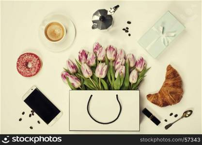 Top view of spring flowers, coffee, mobile phone, croissants, gift and cosmetics. Flat lay image. Holiday, romance of modern life concept