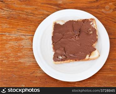 top view of sweet sandwich from fresh toast with chocolate spread, table knife on wooden table