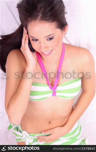 Top view of teen girl laying on her bed talking on her cell phone