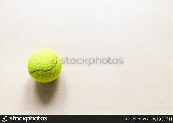 top view of tennis ball on light brown wooden board with copyspace