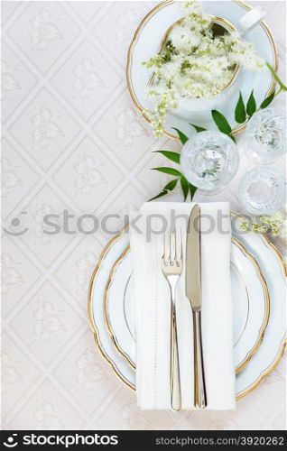 Top view of the beautifully decorated table with white plates, crystal glasses, linen napkin, cutlery and white flower on luxurious tablecloths, top view, with space for text