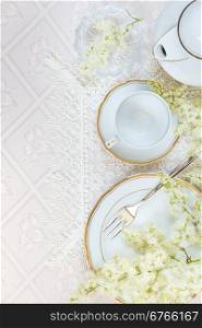 Top view of the beautifully decorated table with white plates, crystal glasses, lace napkin, cutlery and flowers on luxurious tablecloths, with space for text