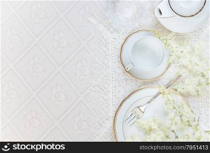 Top view of the beautifully decorated table with white plates, crystal glasses, linen napkin, cutlery and flowers on luxurious tablecloths, with space for text