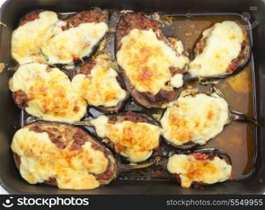 "Top view of the Greek dish of aubergines stuffed with minced beef, onion and tomatoes, topped with bechamel sauce and cheese, fresh from the oven. The dish is called melitzanes papoutsakia, or "aubergine little-shoes""