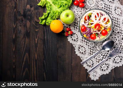 Top view of the healthy colorful fresh salad bowl with quinoa, tomatoes, and mixed greens vegetable in a dish on black wooden background, Health snack food