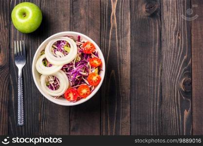 Top view of the healthy colorful salad bowl with tomatoes fresh mixed greens vegetable in a dish on black wooden background, Health salad snack food concept