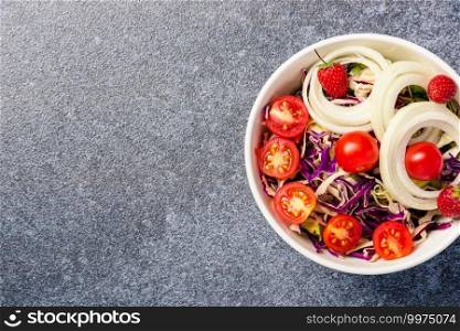 Top view of the healthy colorful salad bowl with tomatoes fresh mixed leaves vegetable in a dish on cement stone table background, Health salad snack diet food weight loss concept
