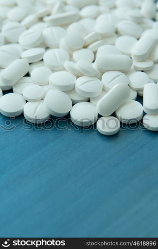 Top view of the Spilled white pills on the blue wooden surface