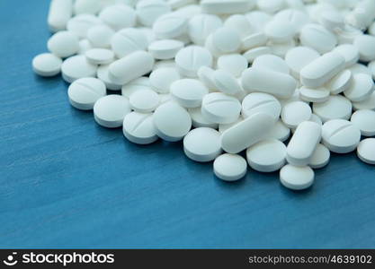 Top view of the Spilled white pills on the blue wooden surface